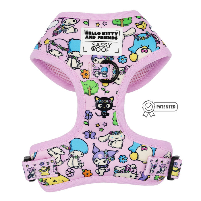 The Sassy Woof Dog Adjustable Harness – Hello Kitty® & Friends Flower Festival features a pastel pink design with colorful characters, black buckle, adjustable straps, brand labels, and a patented badge beside this stylish dog harness.