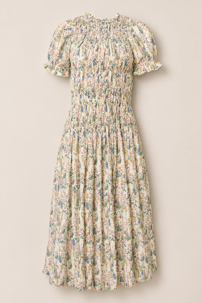 The Jennifer Dress in Autumn Bouquet by Ivy City Co is a light cream dress adorned with a floral print, featuring short puff sleeves, a smocked bodice for comfort, and a gathered midi-length skirt. Maternity friendly and effortlessly elegant, it’s showcased against a plain background.
